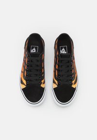 Baskets noires et orange avec un motif texturé. Elles présentent un bout et un talon en suède noir, une semelle blanche en caoutchouc et des lacets noirs.