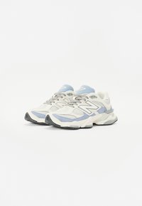 Sneakers in white, light blue, and gray. Features a mesh and suede upper, padded collar, and rubber sole with a textured pattern.