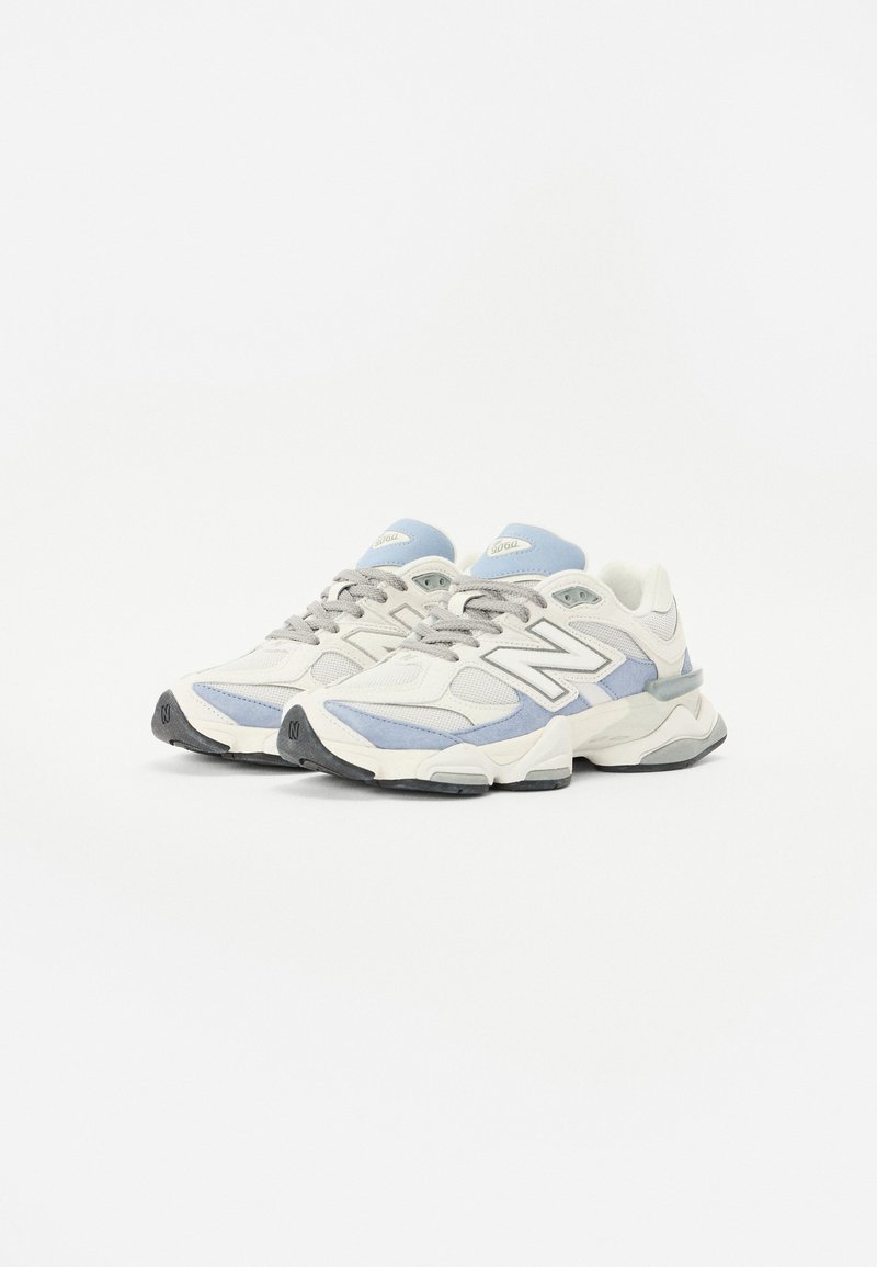 Sneakers in white, light blue, and gray. Features a mesh and suede upper, padded collar, and rubber sole with a textured pattern.