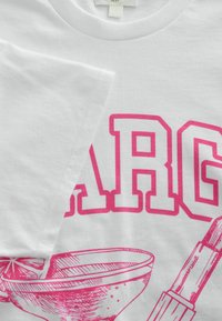 Vit bomull t-shirt med djärv pink grafisk text och illustrationer av en skål och en dryckspinne. Rund halsringning och korta ärmar.