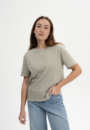 Licht olijfgroene t-shirt met korte mouwen, gemaakt van zachte katoen, met een ontspannen pasvorm en ronde hals, gecombineerd met lichtblauwe jeans.