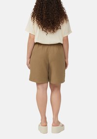 Bruine gestructureerde shorts van lichtgewicht stof, met een elastische tailleband, gecombineerd met een lichtgekleurde, losse top.