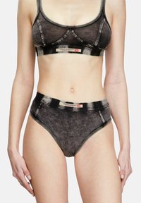Bralette in denim nero con texture e slip a vita alta con cuciture a contrasto e dettagli con logo. Materiale morbido, design aderente, stile minimalista.