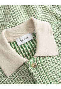 Polo in maglia con motivo a righe verdi e bianche, colletto beige e chiusura con un bottone. Etichetta con la scritta "LES DEUX."