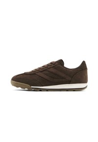 Brown suede athletic shoe with a textured finish, featuring a white midsole, round laces, and a rubber outsole with traction pattern.