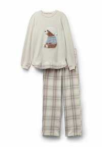 Camiseta de pijama de manga larga color crema con un oso de peluche que lleva un suéter y un gorro azul, combinado con pantalones de pijama a rayas en beige y azul.