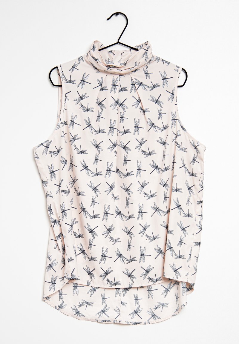 Blouse sans manches rose pâle avec motif de libellules noires, col montant et légers plis, suspendue sur un cintre noir.