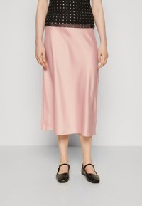 Lys rosa satin midi skjørt med en jevn tekstur, med et enkelt design og rett kant, parret med svarte Mary Jane-sko.