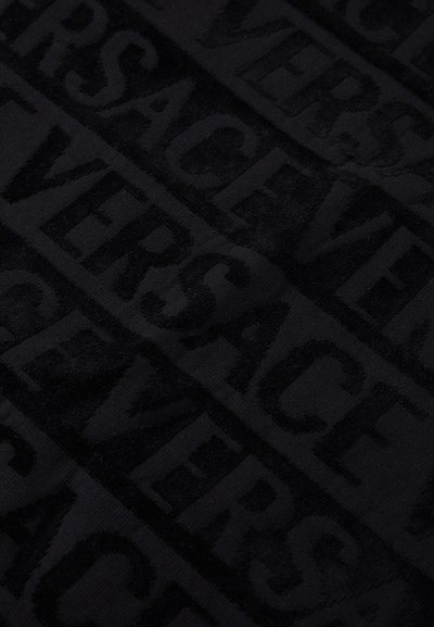 Melna tekstiils, kurā atkārtoti ir izcilas burti, kas veido vārdu "VERSACE", ar mīkstu tekstūru un matētu apdari.