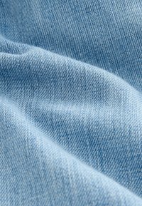 Heled sinine denimkangas, millel on sile tekstuur, näidates peent twill-mustrit ja kergeid värvitoonide varieerumisi.