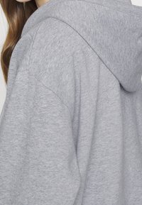 Sudadera con capucha gris hecha de tela suave, con un corte relajado, puños de canalé y una textura suave.