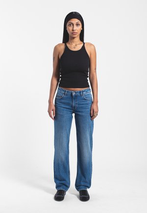Black ribbed tank top paired with light blue straight-leg jeans. The outfit features a smooth texture and casual design, complemented by black shoes.