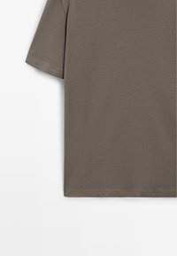 T-shirt en coton vert olive uni à manches courtes, avec coutures visibles sur la manche et l'ourlet, sur fond blanc.