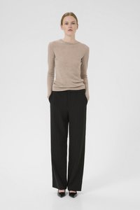 Beige langermet topp kombinert med svarte pinstripe bredbeinbukser og svarte spisse sko. Glatt materiale med tilpassede og skreddersydde detaljer.