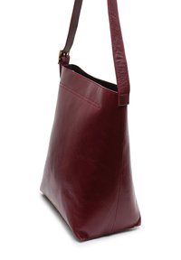 Sac à épaule en cuir bordeaux avec une texture lisse, une silhouette angulaire et une seule sangle ajustable. Présente un design minimaliste avec un détail de couture.