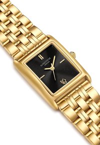 Kullatud tooni ristkülikukujuline kell tekstureeritud musta kellapinnaga, kullast käed ja kudumisest valmistatud randmepael. Sisaldab kahte kullatud tunni markerit ja kroon.