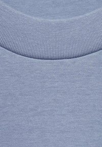 Tessuto di cotone azzurro chiaro con scollatura rotonda a costine. Texture liscia con un motivo a maglia uniforme e senza ulteriori abbellimenti.