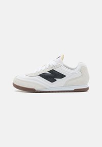 Witte sneaker gemaakt van suede en leer. Voorzien van een zwart accentlogo, witte veters en een rubberen zool. Ronding aan de teen.