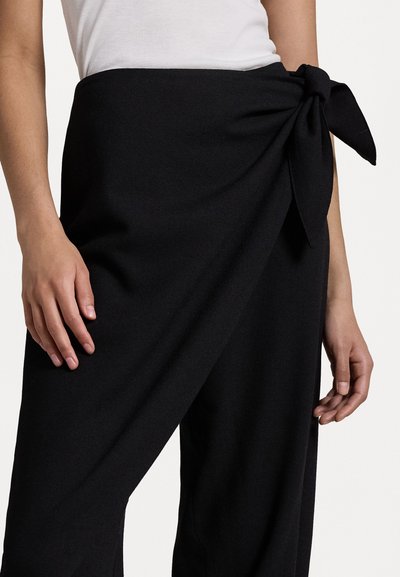 Zwarte wikkelbroek met een zijknoopdetail. Gemaakt van glad, textuurstof. Heeft een hoge taille en een wijd model.