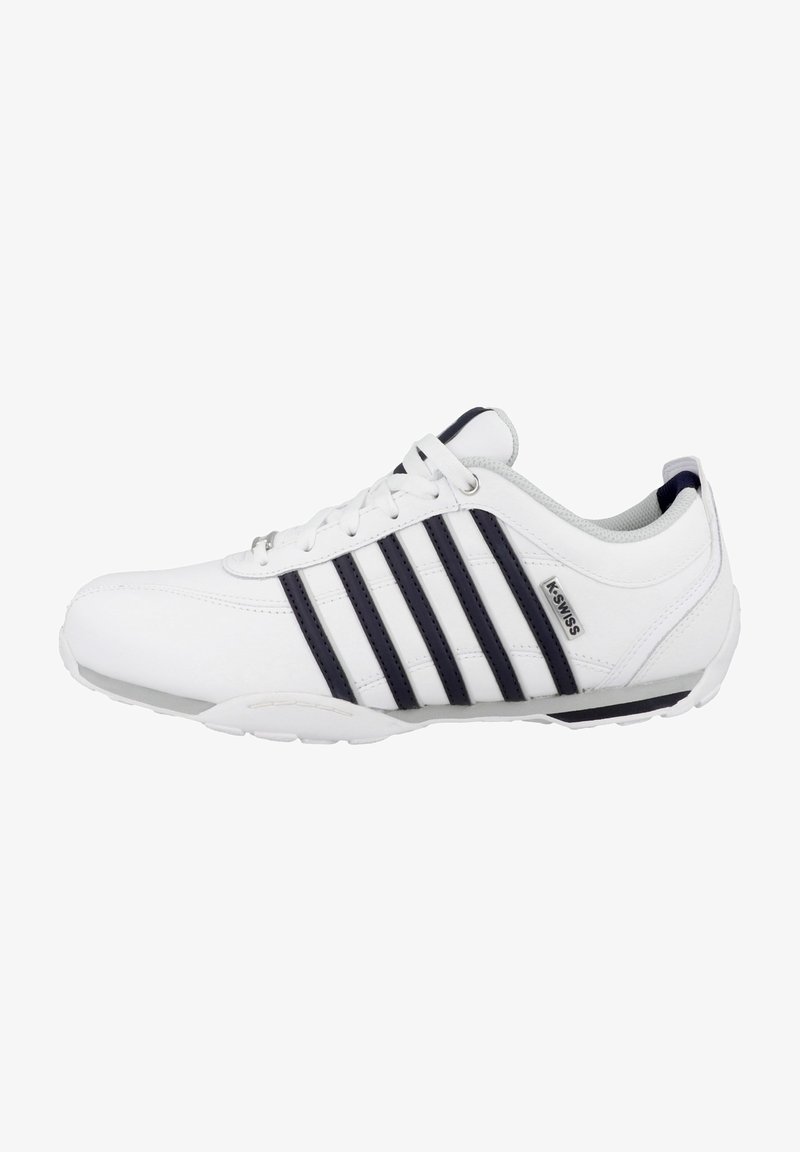 Witte sportieve schoenen met een glad leren bovenwerk, voorzien van drie donkerblauwe strepen, een gevoerde kraag en een flexibele witte zool.