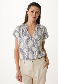 Blusa a maniche corte con scollo a V in crema con motivo geometrico blu, caratterizzata da un colletto arricciato e una texture di tessuto leggera e liscia.