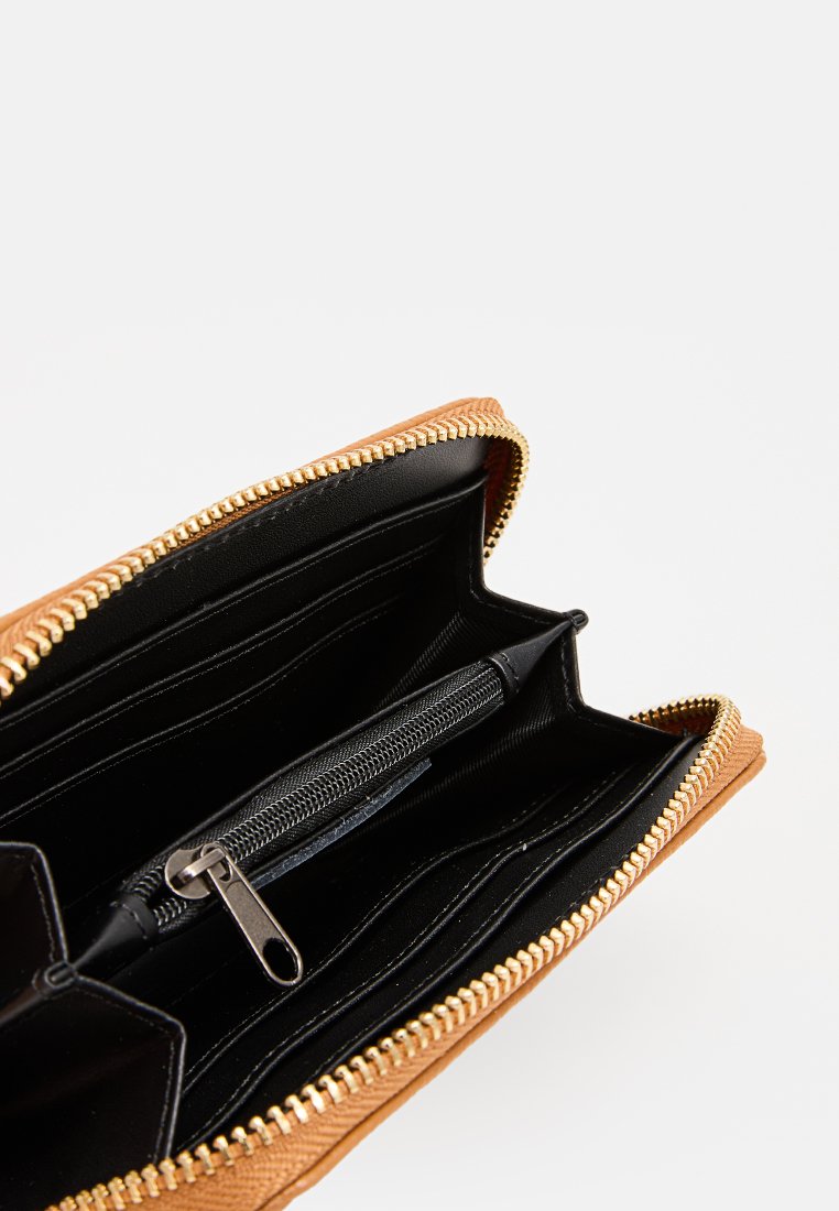 Portefeuille en cuir marron ouvert avec une fermeture éclair dorée, des compartiments intérieurs noirs, des emplacements pour cartes et une poche à pièces zippée centrale.