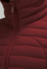 Bordowa kurtka puchowa z zamkiem z przodu i wysokim, wyściełanym kołnierzem, prezentująca pikowane poziome przeszycia na materiale.