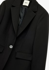 Sort blazer lavet af glat stof, med en struktureret design, klippet revers, enkelt knaplukning og to forlommer.