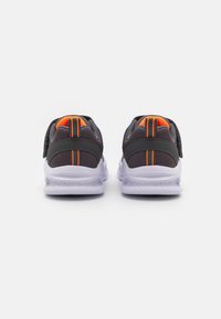 Zapatillas deportivas grises con acentos naranjas, fabricadas con material de malla, correas de Velcro y una suela blanca con un patrón texturizado.