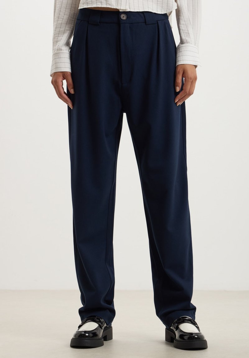 Pantaloni a gamba larga blu navy realizzati in tessuto morbido, con chiusura a un bottone e pieghe frontali per un tocco di stile.