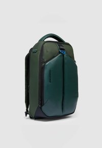 Zaino verde con una combinazione di tessuto testurizzato e materiale liscio, doppia chiusura a zip e maniglia superiore con un dettaglio blu.