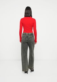 Rød stripete langermet topp kombinert med høyt liv, vide ben, falmede svarte jeans. Antrekket har et enkelt design uten synlige mønstre.