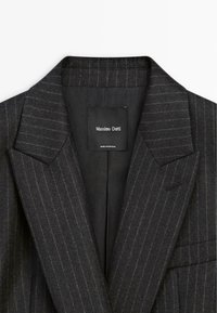 Donkergrijze pinstripe blazer met een gelapte kraag, gestructureerde schouders en een zwarte voering. Etiket leest "Massimo Dutti, Made in Portugal."