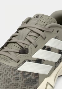 Αθλητικά παπούτσια με υφή γκρι επάνω μέρος με επενδύσεις από δίχτυ, λευκές ρίγες και μπεζ κορδόνια. Διακριτική αδιάβροχη σήμανση.