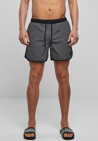 Shorts de bain gris avec accents noirs, taille élastique et cordon de serrage. Tissu léger et à séchage rapide avec une texture lisse.