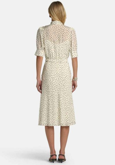Krém színű ruha fekete pöttyökkel, rövid buggyos ujjak, deréknál ráncolt, térd alá érő szoknya, áttetsző anyagból, gallérral kiegészítve.
