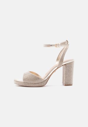 Open hiel sandaal met hoge hak, enkelbandje, blokhak en sprankelende strassversieringen op een metalen basis.