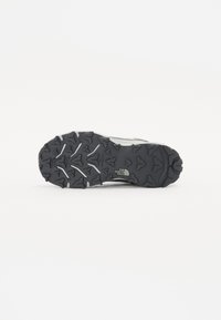 Semelle en caoutchouc noir avec un motif de semelle extérieure robuste, présentant des formes variées pour une meilleure traction ; marquée du logo "The North Face".