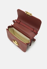 Rød læderhåndtaske med struktureret overflade, guldfarvet hardware og en rem. Indvendigt har den en beige foring og en lille kortholder.