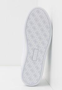Semelle de sneaker blanche avec surface texturée, comportant un motif de logo répété. Caoutchouc solide avec un bord lisse et une forme plate.