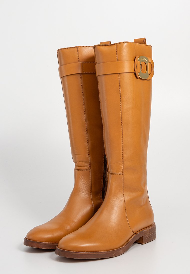 Hoge leren laarzen in een warme tan kleur, met een zijrits, een brede band met een gespsaccent en een lage, platte houten hak.