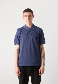 Marineblaues Poloshirt aus strukturiertem Stoff, mit einer Zwei-Knopf-Leiste und gesticktem Logo auf der Brust. Kurze Ärmel, lockere Passform.