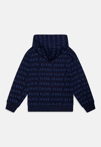 Mörkblå hoodie med ett genomgående upprepande mönster av texten "Calvin Klein Jeans" i ljusare blått, med huva och ribbade ärmslut.