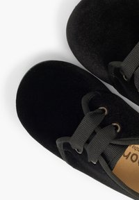 Scarpe in tessuto nero con punte rotonde, superficie testurizzata, lacci neri e occhielli metallici. Questo design presenta un rivestimento interno morbido.