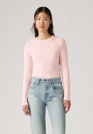 Long-sleeve pink top made of soft fabric with a round neckline, paired with high-waisted light blue jeans featuring a slight distressed detail.