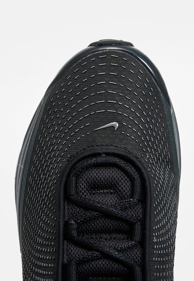 Gros plan sur l'orteil d'une chaussure de course Nike noire avec un dessus texturé, des lacets noirs et un petit logo swoosh Nike argenté centré près de la zone des lacets.