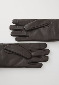 Σκούρες καφέ δερμάτινες γάντια με λεία υφή, τοποθετημένα επίπεδα σε λευκή επιφάνεια, δείχνοντας τις μπροστά και πίσω πλευρές.