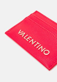 Crvena teksturirana futrola za kartice s sjajnim zlatnim logotipom "VALENTINO", koja ima više utora za kartice i elegantan pravokutni oblik.