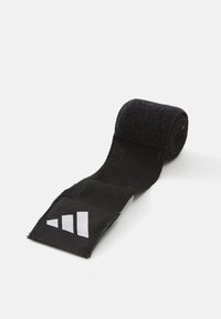 Svart elastisk sportstropp med en texturerad yta, med en vit logotypklistermärke med tre diagonala ränder. Rullad upp för förvaring.