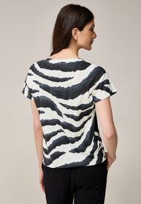 Korte mouw t-shirt met een zwart-wit zebra-strip patroon, ronde halslijn en een relaxed fit. Zachte stof met een gladde textuur.